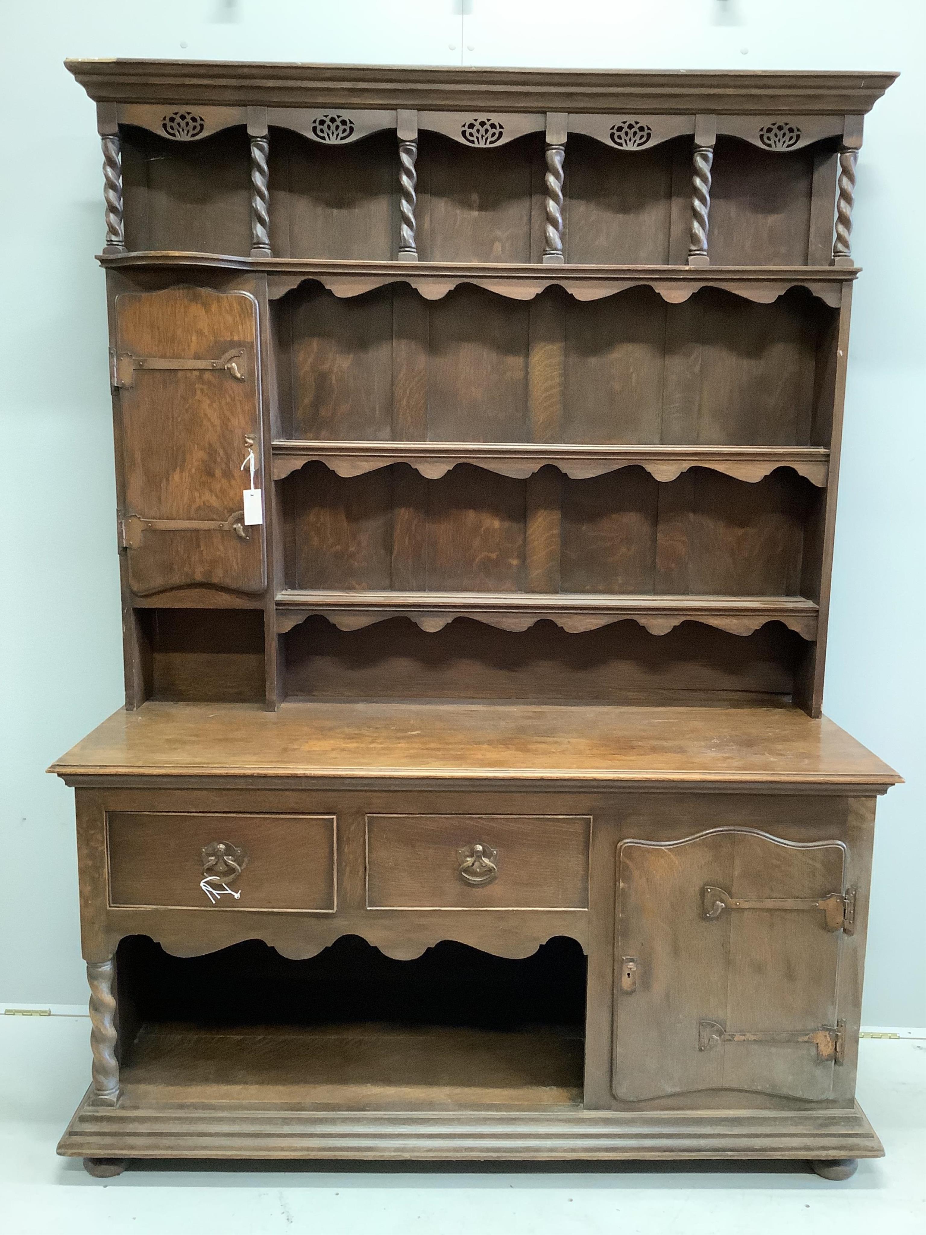 An early 20th century Liberty style oak dresser, width 157cm, height 208cm. Condition - damage to the top left of the cornice otherwise looks to be in good order